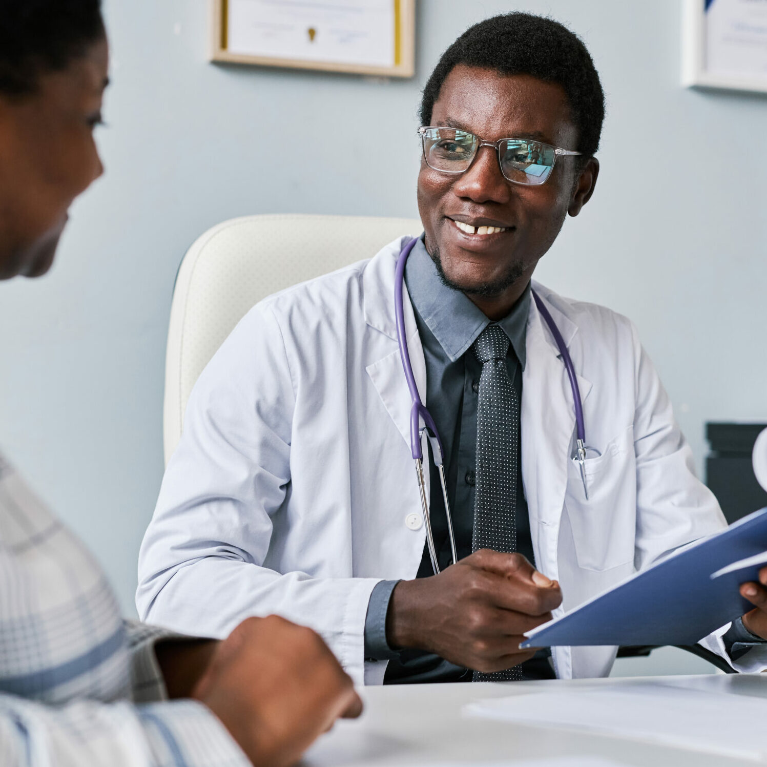 Portrait of smiling black doctor consulting female doctor in private clinic